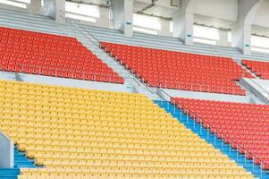 asientos vacíos de color naranja y amarillo en el estadio, filas de asientos en un estadio de fútbol foto