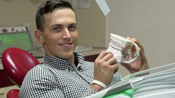 Handsome young man examining dental mold, smiling to the camera video