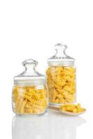 Raw pasta in glass jar isolated on white background photo