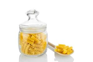 Raw pasta in glass jar isolated on white background photo