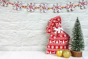 Decorative christmas tree, red gift bag and golden balls on white wooden background. photo
