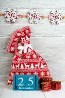Decorative christmas gift boxes, red gift bag and blue perpetual calendar on white brick wall. photo
