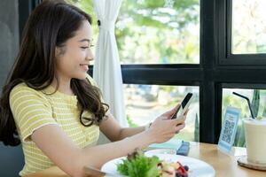 Woman use smartphone to scan QR code to pay in cafe restaurant with a digital payment without cash. Choose menu and order accumulate discount. E wallet, technology, pay online, credit card, bank app. photo