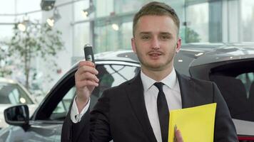 Professional car salesman holding car key, looking to the camera confidently video