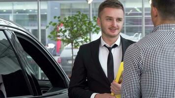 Car dealer shaking hands with male customer after selling an automobile video