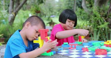 een meisje en een broer zijn spelen met plastic puzzels. video
