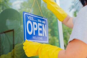 The owner of the store hangs a sign to open a business in front of the door. photo