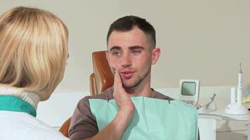 masculino paciente com dor de dente falando para dele dentista às a hospital video