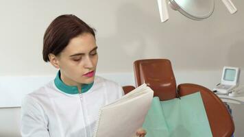Charming female dentist working at her office, filling medical papers video