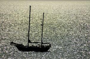 a sailboat is seen in the water near the shore photo