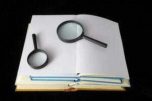 a magnifying glass and an open book on a black background photo