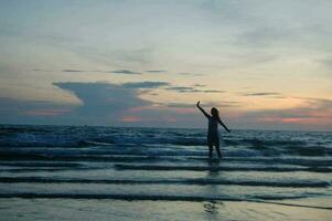 a woman standing on the beach with her arms outstretched photo