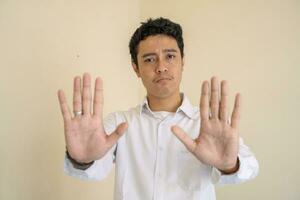 Young Indonesian curly man wear white clothes with stop pose. photo