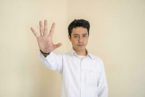 Young Indonesian curly man wear white clothes with stop pose. photo