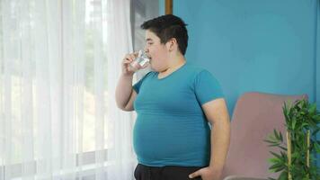 Obesity boy drinking water in front of glass, feeling happy and relaxed. video