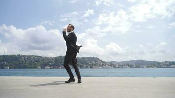 Businessman shouting for his success against the sea. video