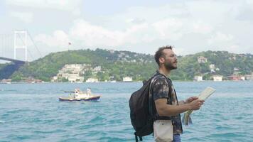 turista segurando uma mapa é caminhando de a mar. video