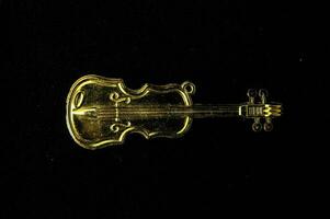 a gold tone violin charm on a black background photo