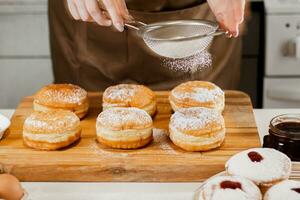 Woman chef prepares fresh donuts in her bakery. Cooking traditional Jewish Hanukkah Sufganiyot. Small business concept. photo