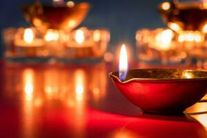 Happy Diwali. Burning diya oil lamps and flowers on blue background. Traditional Indian festival of light. photo