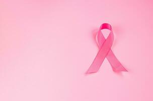 Pink ribbon on colored background. Breast Cancer Awareness Month symbol. Women's health care concept. Promotion of campaign to fight cancer. photo