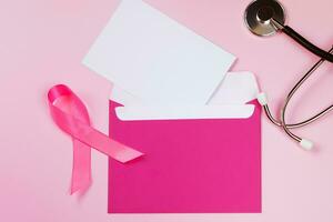 Breast Cancer Awareness Month. Women's health care concept. Pink ribbon and stethoscope on colored background. Envelope mockup. photo