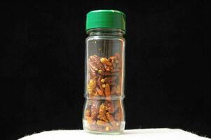 a bottle filled with dried chili peppers photo