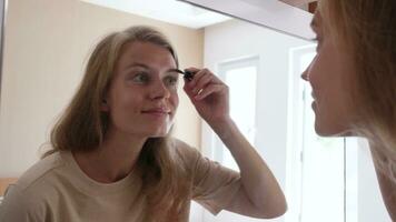lindo mulher fazer acima de a espelho dentro hotel quarto , escovar sobrancelhas video