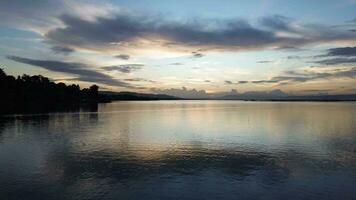 Aerial view over the water of the lake with sunset views and sun reflections. Aerial view of lake. Flying over water. Flight over calm lake surface video