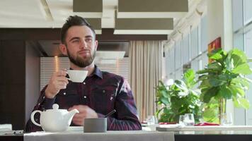 Bearded handsome man looking away thoughtfully, enjoying morning tea video