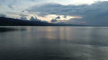 Aerial view over the water of the lake with sunset views and sun reflections. Aerial view of lake. Flying over water. Flight over calm lake surface video