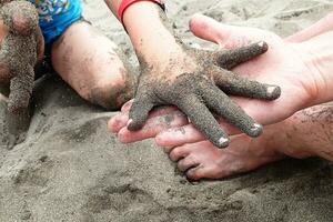 l niño mano en de cerca en el playa con multa arena atascado en el dedos foto