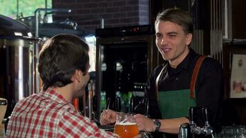 Lycklig man talande till en bartender medan har öl på lokal- pub video