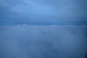 original sunrise landscape over dark clouds seen from the window of an aircraft photo