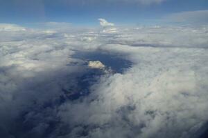 white clouds against the blue sky seen from the flight from the windows of the plane photo