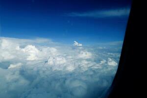 blanco nubes en contra el azul cielo visto desde el vuelo desde el ventanas de el avión foto