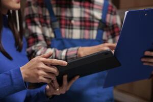 Warehouse managers tracking parcel on digital tablet and checking customer orders list on clipboard. Retail ecommerce storehouse employees managing inventory in storage room photo