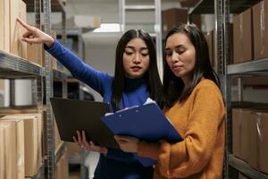 Warehouse worker and supply chain manager tracking inventory in storage room. Storehouse employees planning parcel stocking process optimization, analyzing orders checklist on clipboard photo