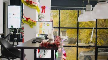 Empty stylishly festive ornate modern office workspace with beautifully decorated Christmas tree. Business charts on computer screen in xmas adorn workplace during winter holiday season photo