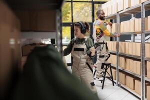 Employee listening music at headphones during inventory in warehouse, scanning cardboard box barcode using store scanner. Storage room supervisor preparing customers orders working at shipping photo
