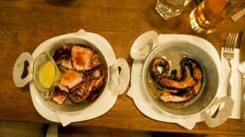 Zoom in footage on two plates with gourmet seafood in them. Fried octopus and squid with souce video