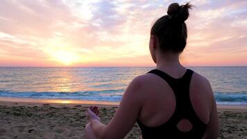 Woman on the beach practicing yoga at the sunrise. There is a scenic imagenery and panorama video