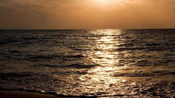 water spatten in de zee Bij de zonsopkomst met zon stralen reflectie in de water video