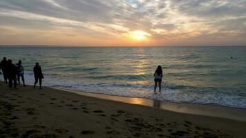 persone silhouette a piedi su il spiaggia a il Alba. viaggiare, vacanza e rilassamento video