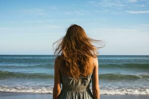 espalda ver de un joven mujer en pie en el playa y mirando lejos, posterior ver de un mujer disfrutando el ver a el playa o océano, ai generado foto