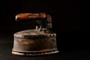 an old iron with a wooden handle on a black background photo