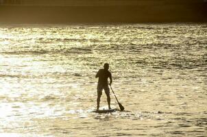 a man is standing on a paddle board in the water photo