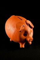 a clay pig bank on a black background photo