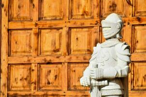 a statue of a knight standing in front of a wooden door photo