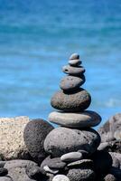 a stack of rocks on the beach by the ocean photo